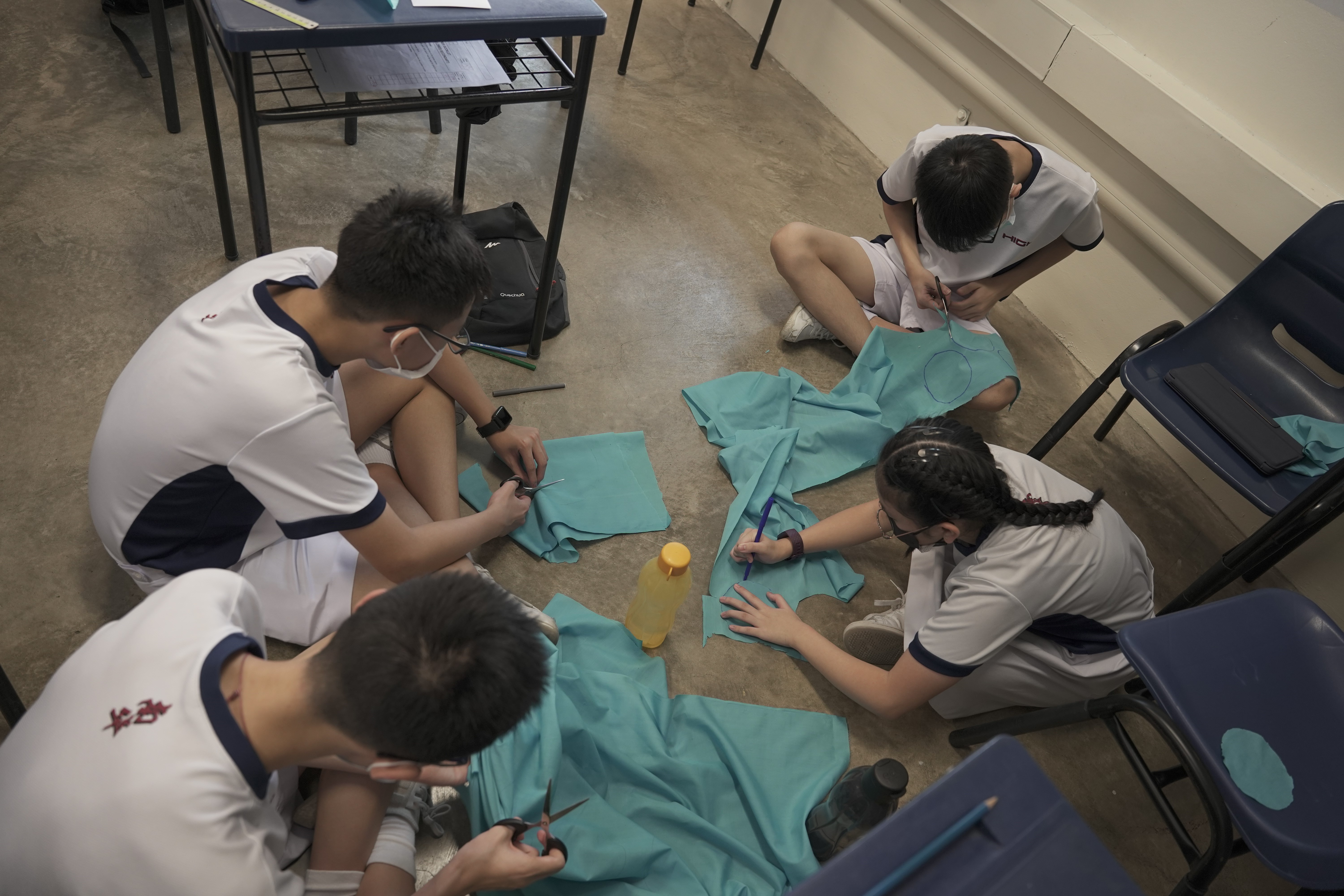 Secondary 2 students cutting recycled fabrics to create fabric flowers