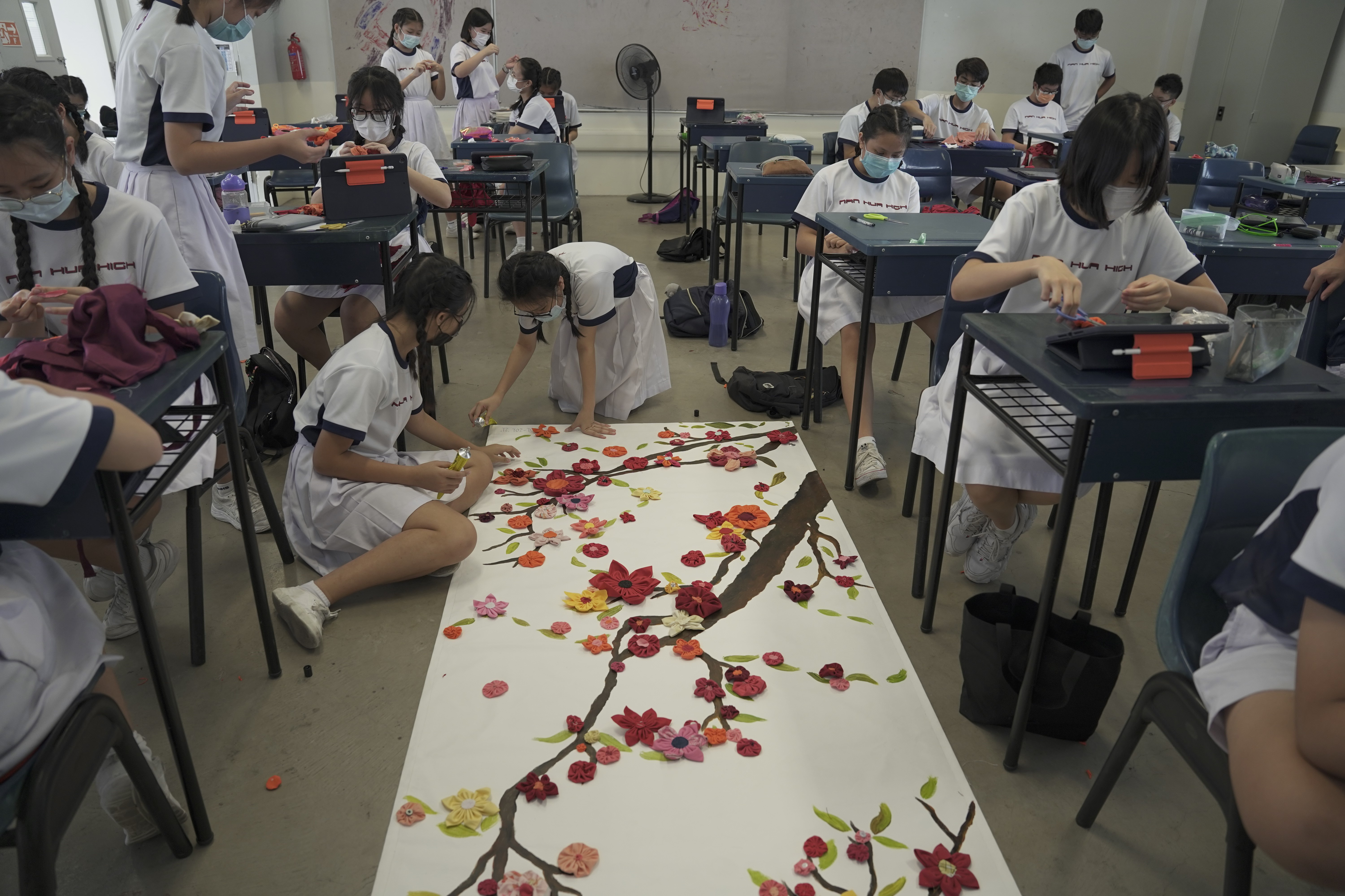 Secondary 2 students placing fabric flowers on canvas for Artsfest 