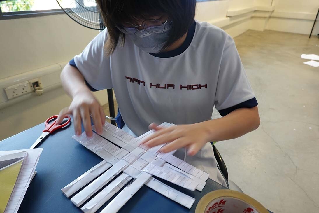 A student making her recycled paper basket.JPG